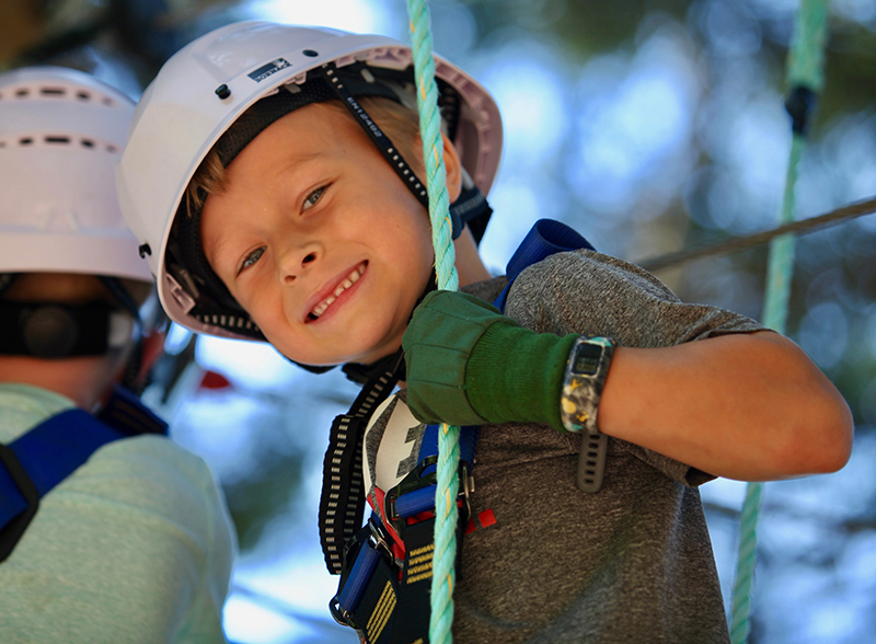Young boy smiling and wearing safety harness, helmet and gloves